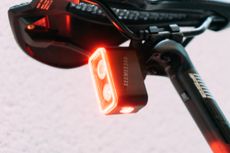 A close up of a rear bike light with two bulbs and one bulb underneath