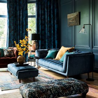 Teal living room with wall panelling, two sofas and two upholstered ottomen