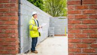 A building inspector looking at a brick and concrete block shell of a house