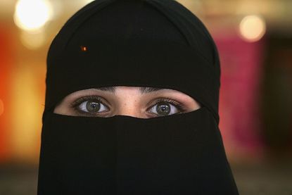 A Muslim woman wearing a Niqab poses inside a shop in the British northern town of Blackburn.