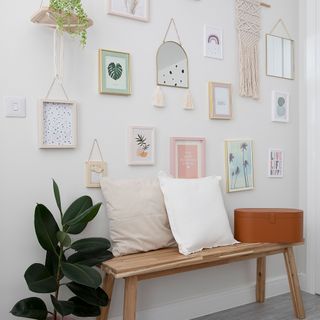 gallery wall on white background with wooden bench cushions and rubber plant