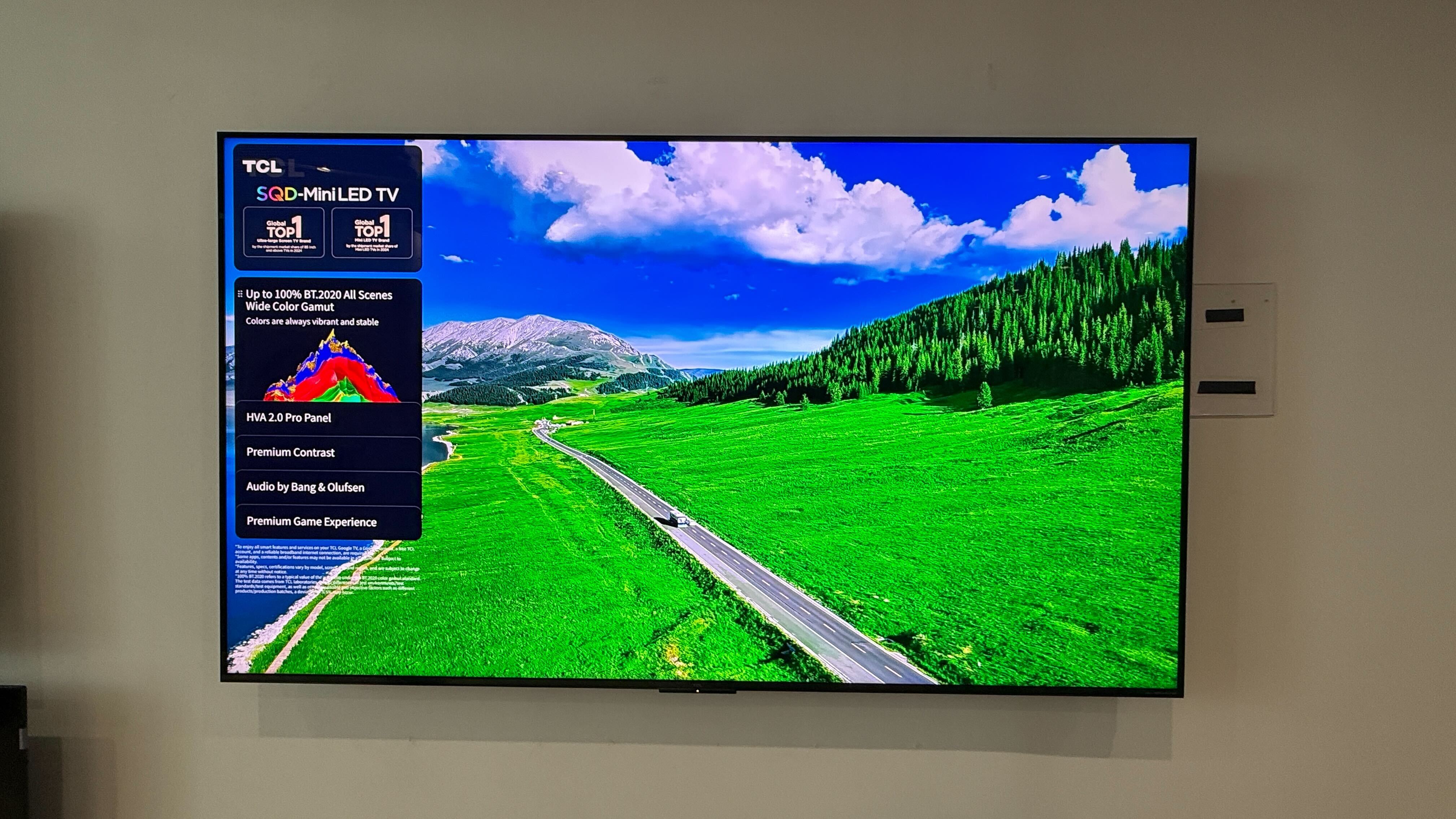 Wall-mounted TCL C7L with vibrant demo content on screen