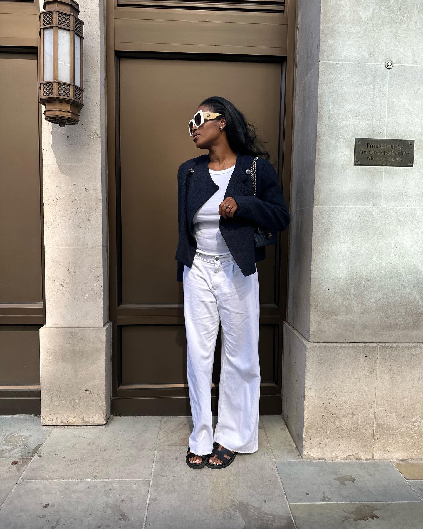 Influencer wears white jeans and black sandals.
