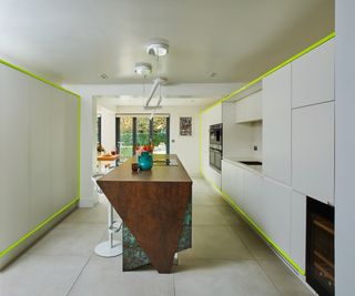 large long galley kitchen with white units, green LED lighting and feature kitchen island in wood and marble in centre