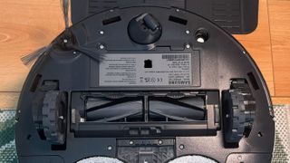 Underside of Samsung Jet Bot Combo AI robot vacuum, showing rollers and side brush