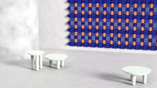 A wall featuring a composition of chunky tiles in blue and orange, shown in a white room with monochrome white furniture, by Tomma Bloom at Wanted Design 2021