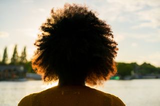 Woman with afro looking at sunsent