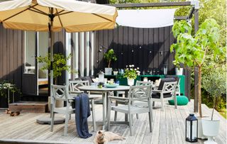 Grey garden dining set with beige parasol and light decking