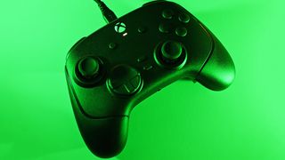 Top-down view of the black Razer Wolverine controller connected by a USB cable, illuminated under vivid green ambient lighting.
