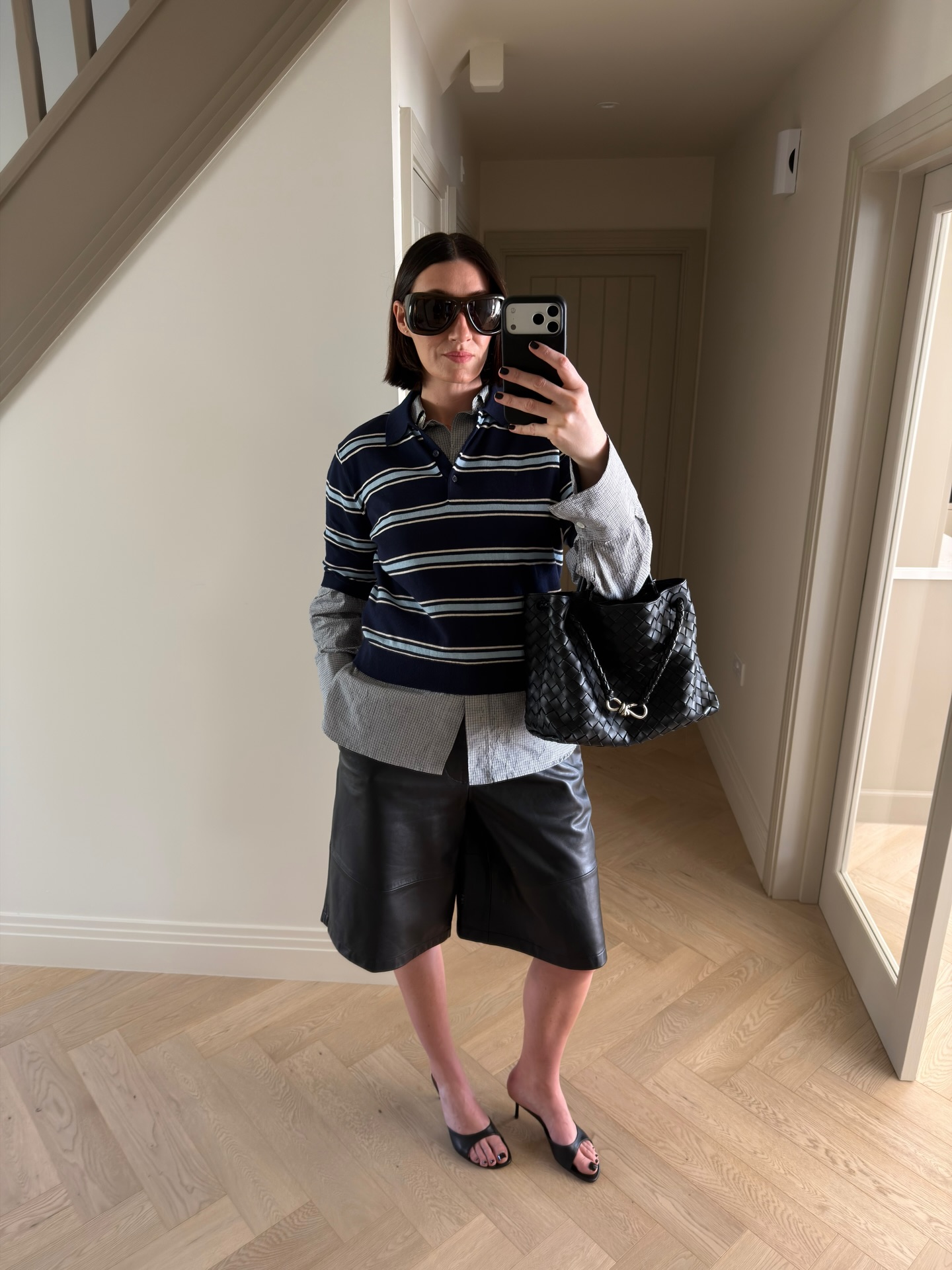 Sarah wears a rugby top over a shirt with leather shorts and mules