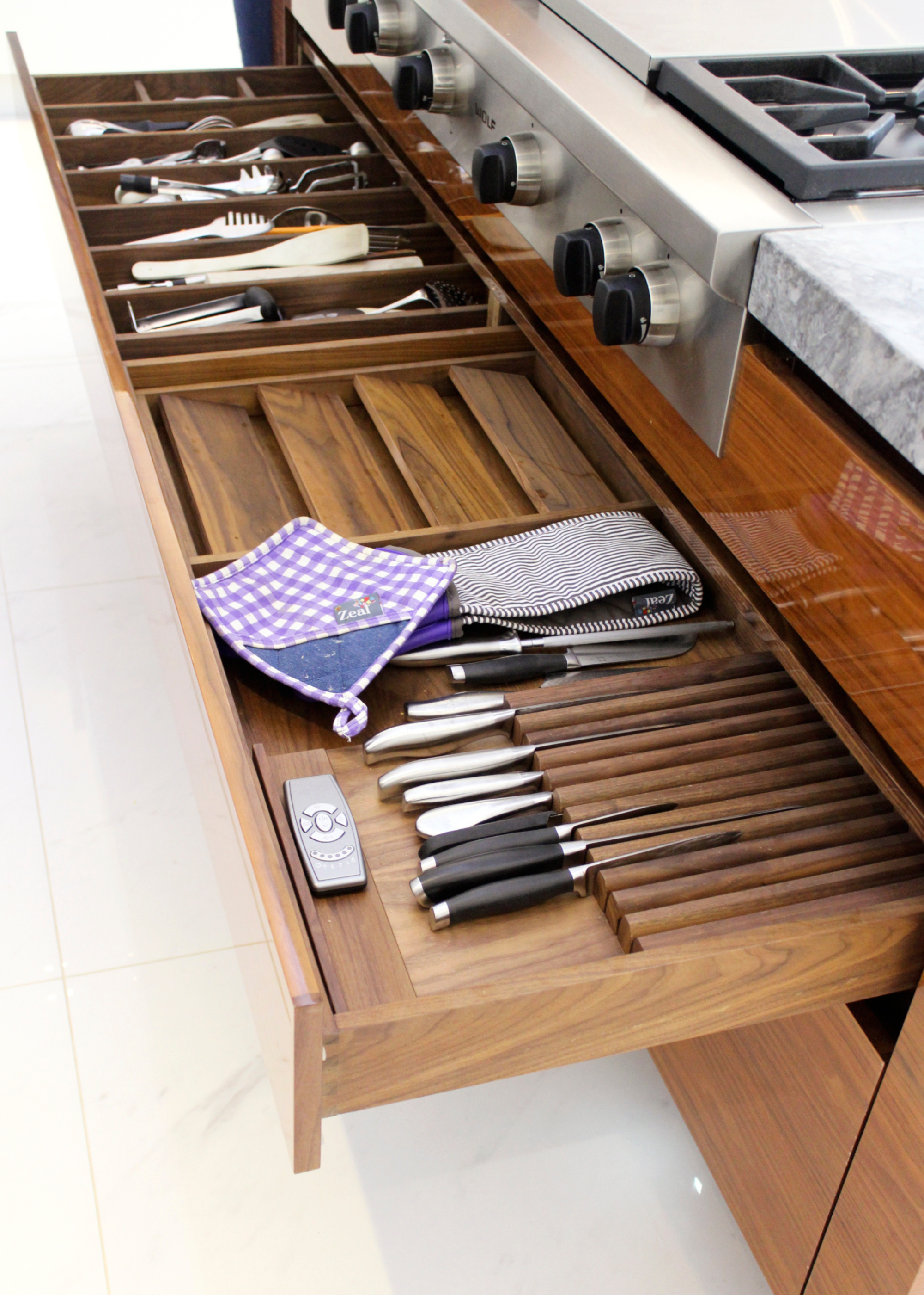 A large wooden kitchen drawer with cutlery organizer, knife slots and spice rack
