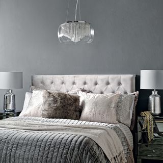 Glam grey bedroom with light grey upholstered headboard and glam bedside lights and pendant