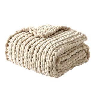 A folded white knitted throw blanket