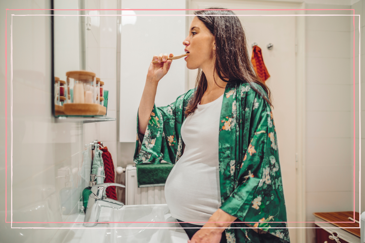 Pregnant woman with sensitive teeth brushing in the mirror 