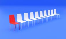 image of several white chairs in a row with one red chair against a blue background