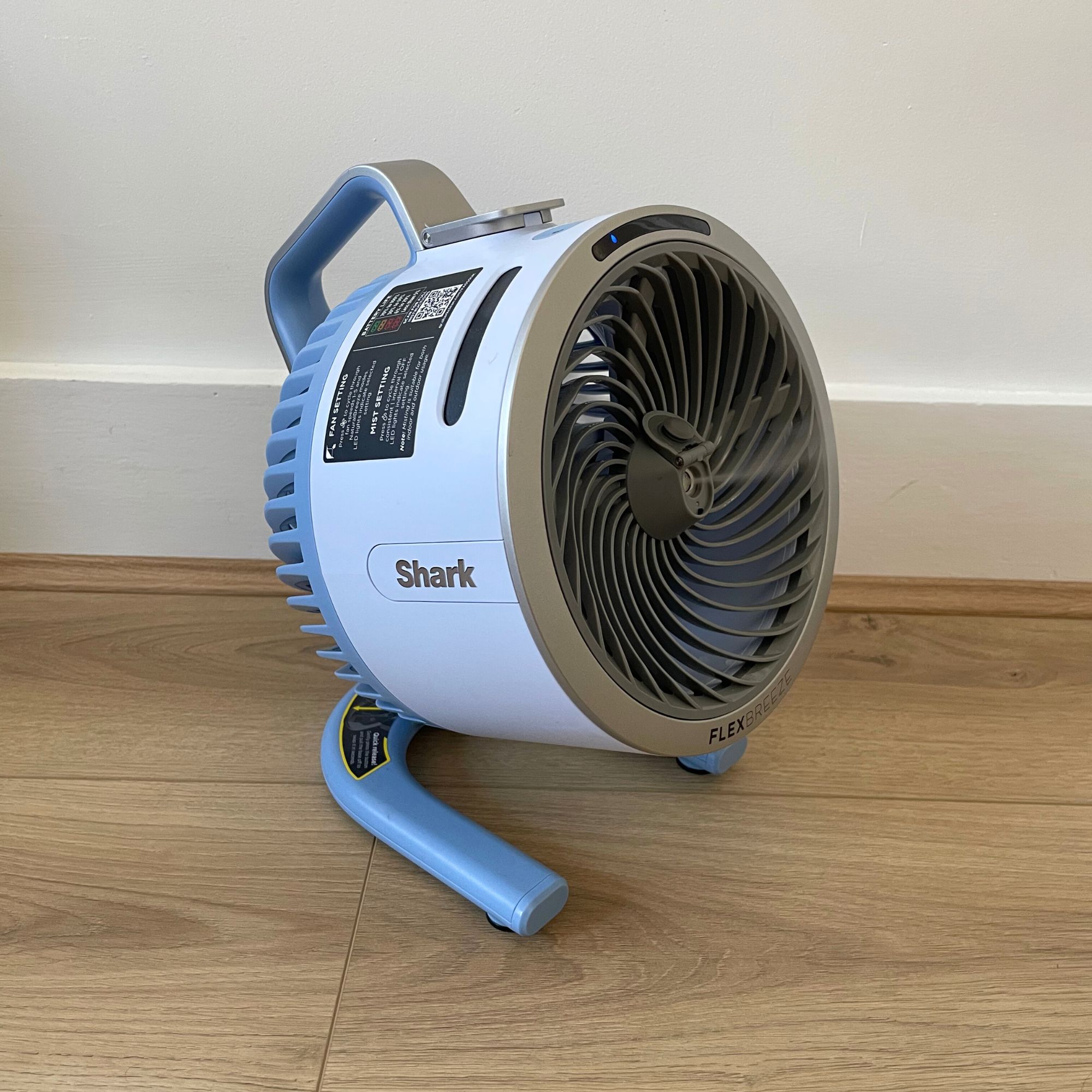 Blue Shark Hydrogo misting fan sitting on the floor in front of a white wall