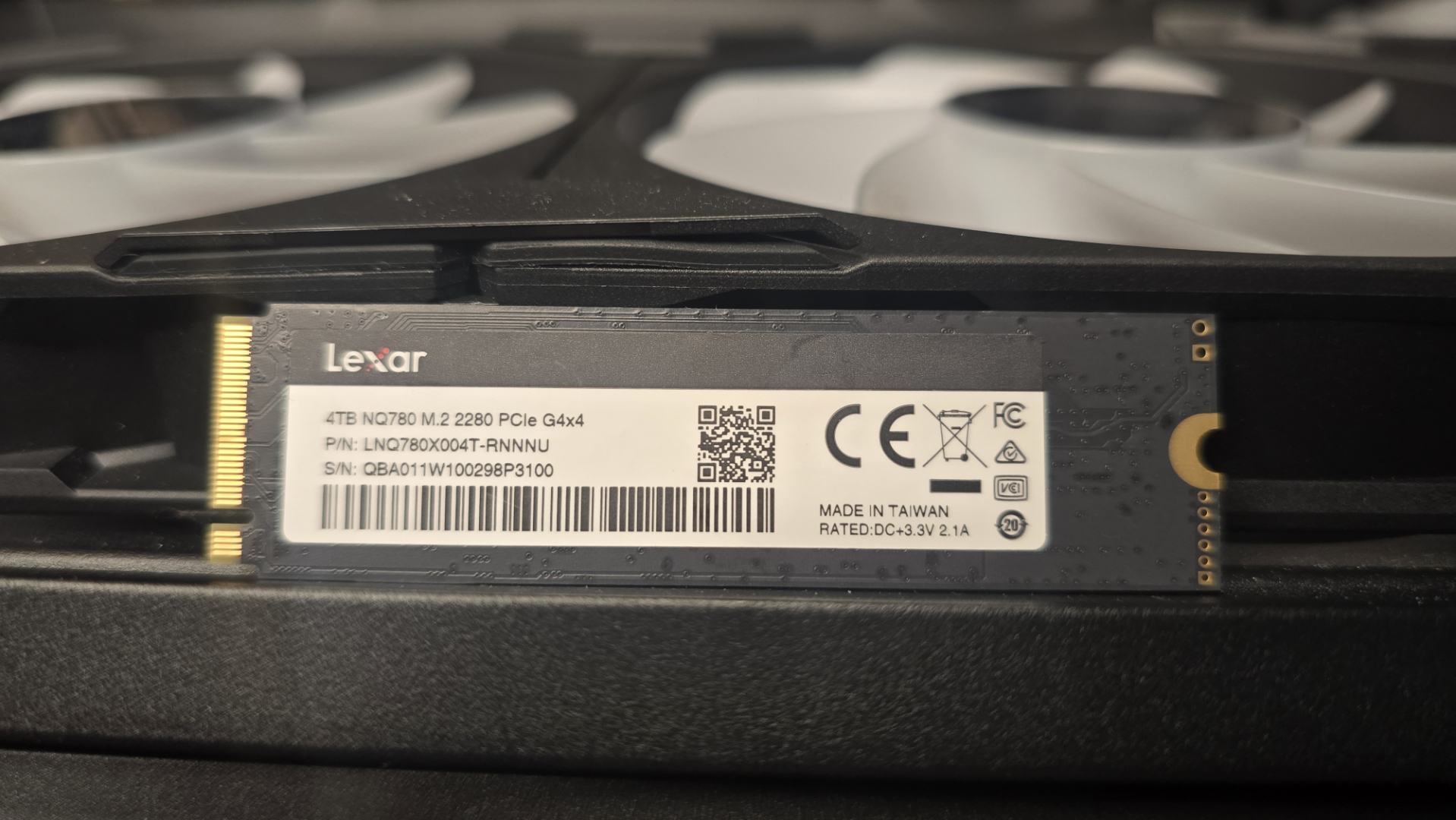 A Lexar NQ780 SSD installed inside a gaming PC and on top of a graphics card.
