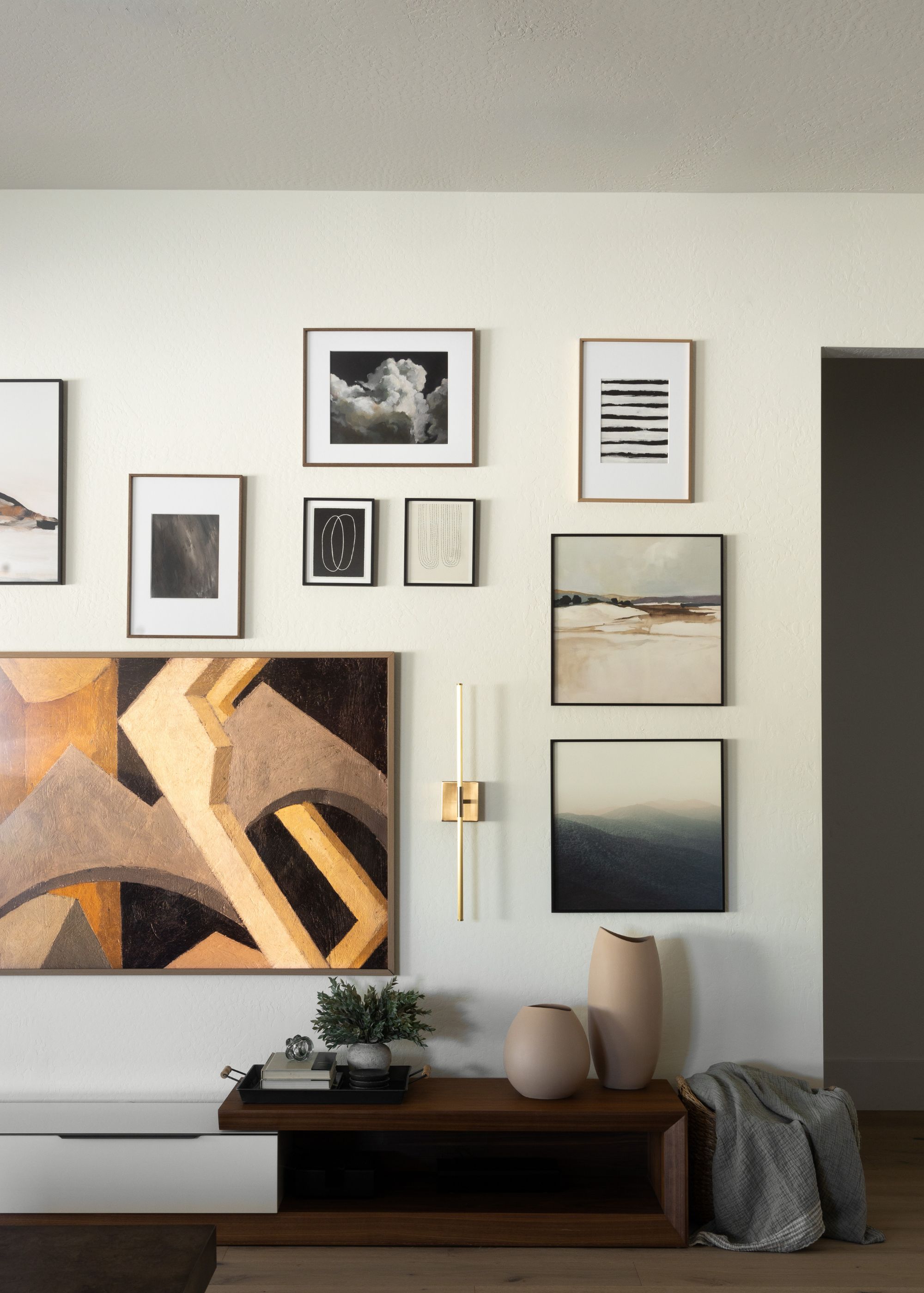 A gallery wall with an art tv as well as other framed art pieces around it. At the bottom is a table with two decorative vases as well as coffee table books