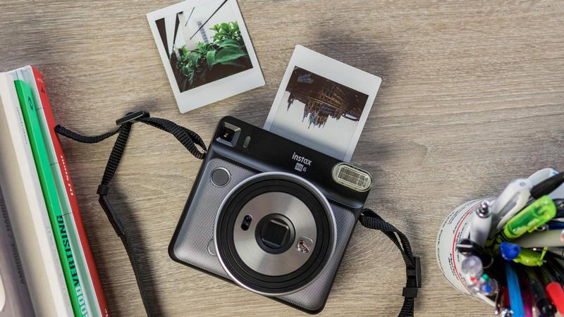 A Fujifilm Instax Square SQ6 instant camera on a wooden table