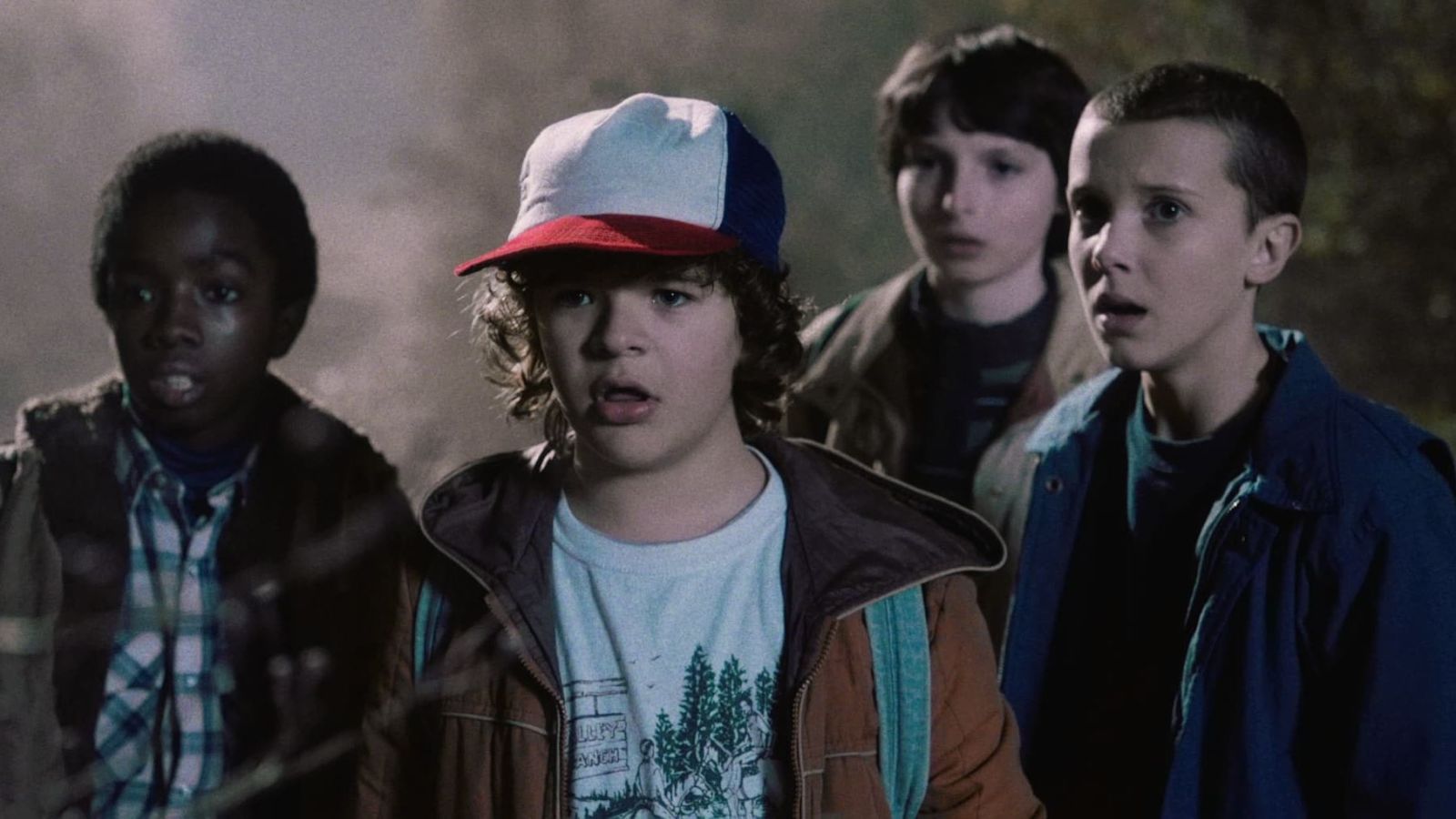a group of little kids look scared into the distance in a still from stranger things season 1
