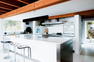 modern white kitchen with island in a self build home with timber beams