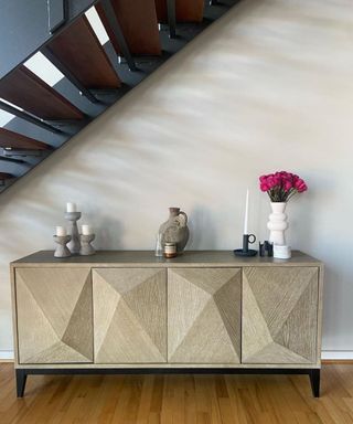 A gold console table with decor on underneath a staircase