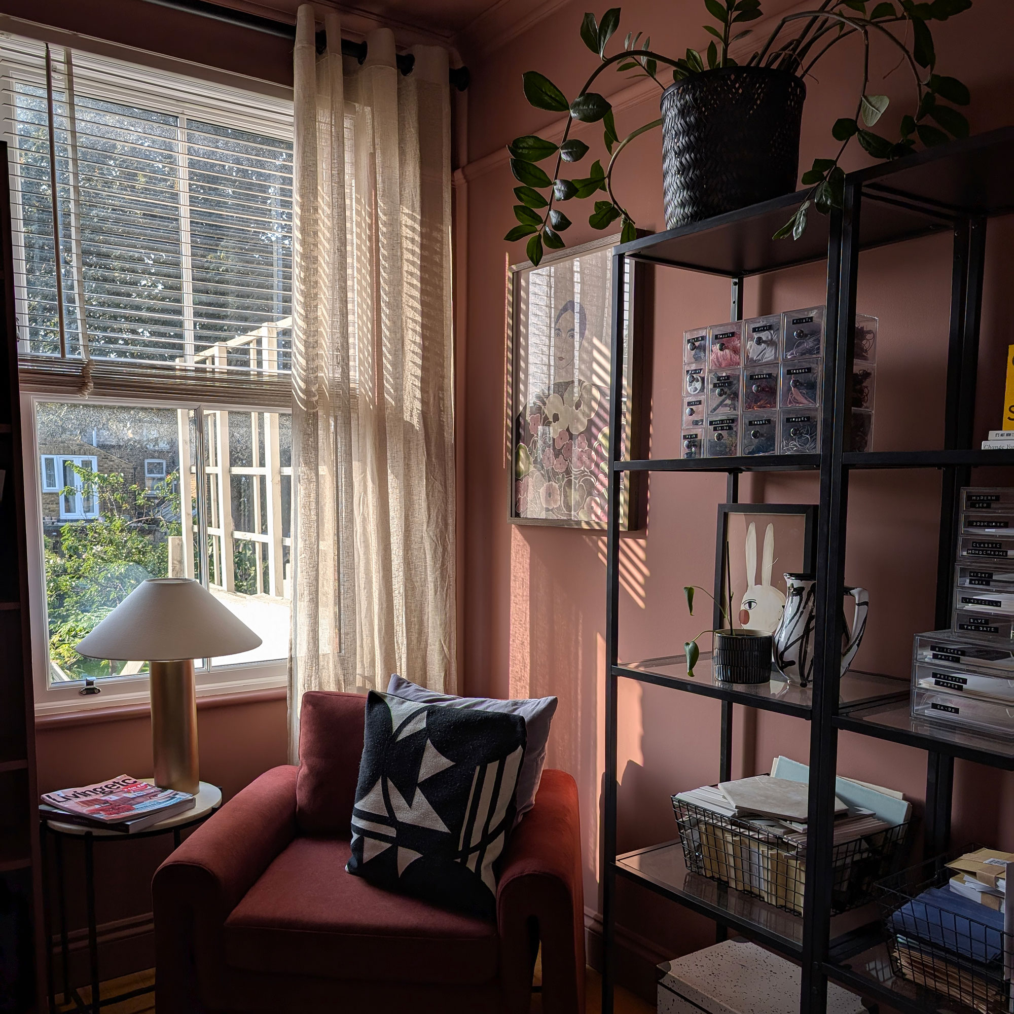 Terracotta room with open shelving, armchair, side table and lamp