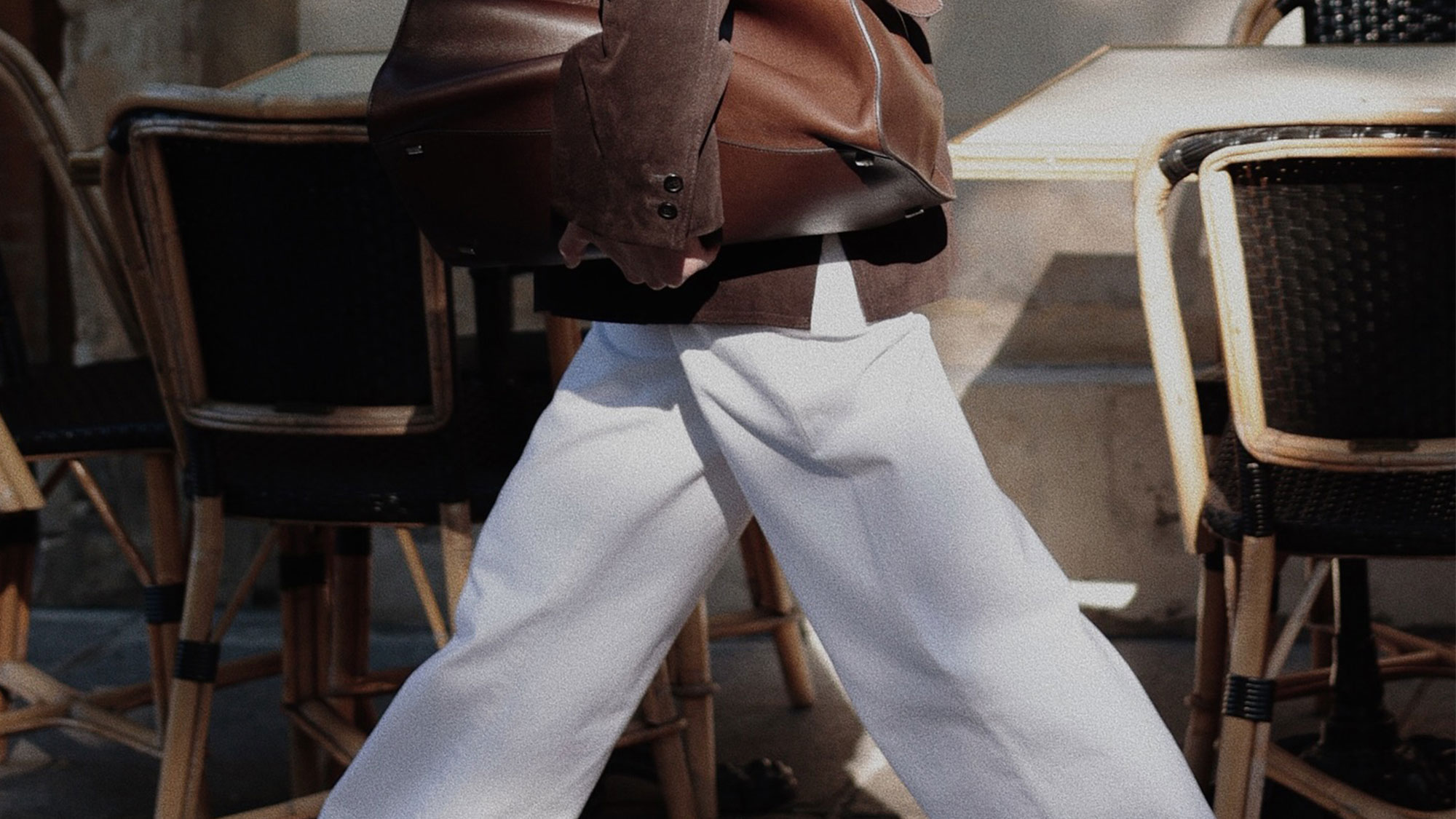 Woman wearing white jeans and a brown suede jacket.