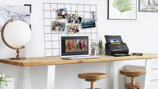 One of the best photo scanners on a worktop beside a laptop and a selection of photos