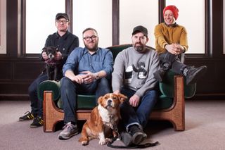 The four members of the band Mogwai (and two dogs) sitting on a sofa