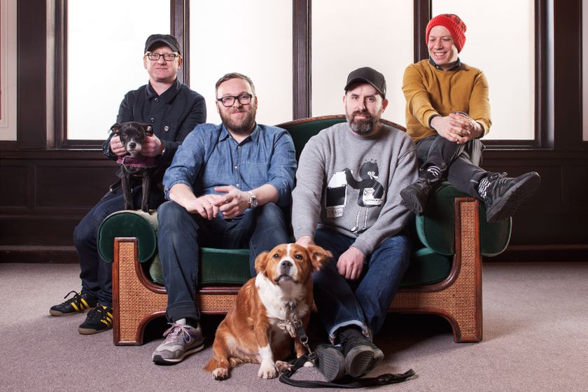 The four members of the band Mogwai (and two dogs) sitting on a sofa