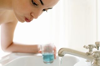 Woman using mouthwash