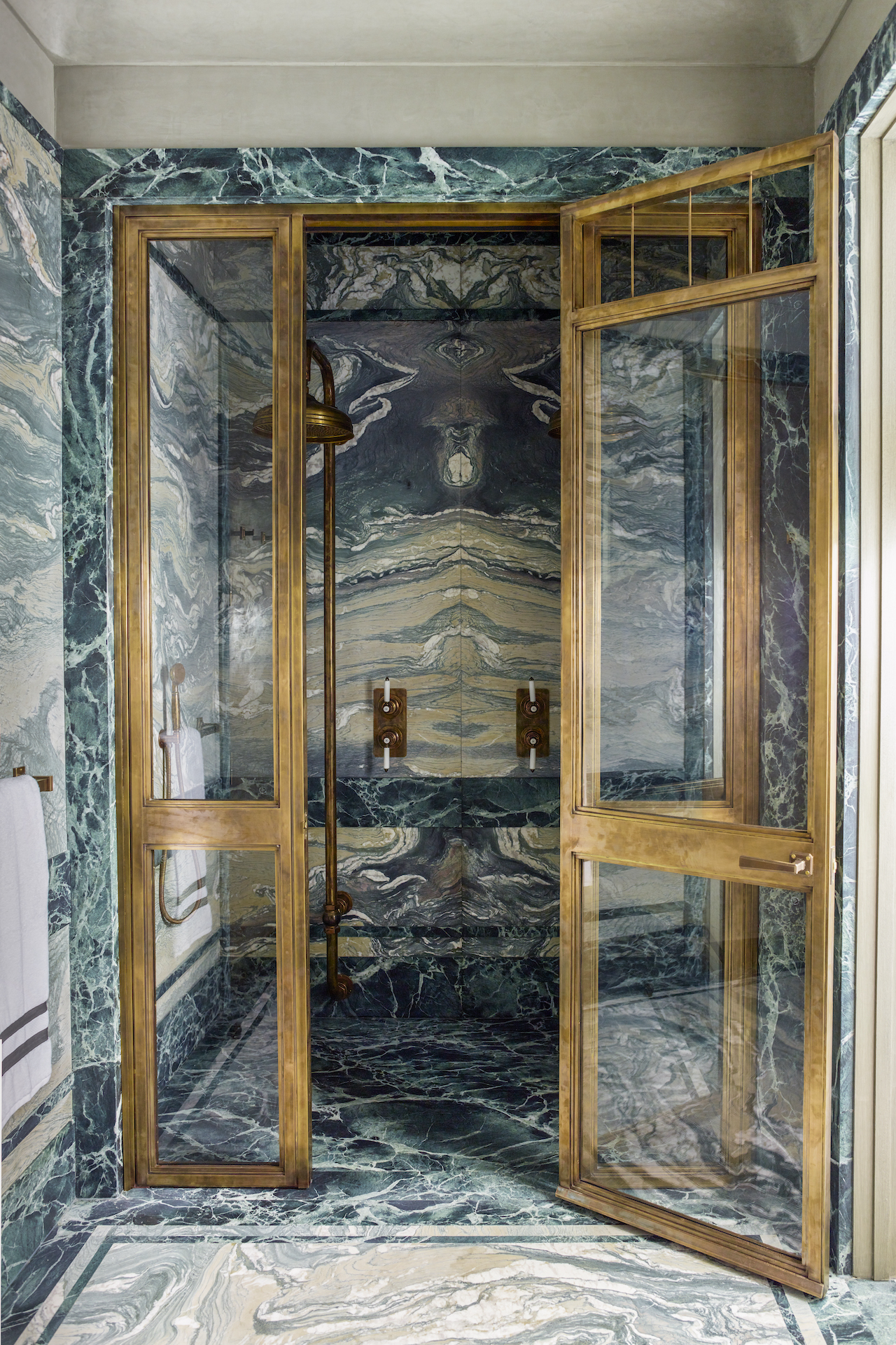 A green bathroom shower with a green marble dual shower with wooden shower doors