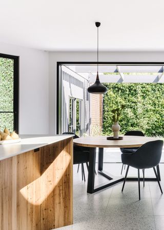 A dining table placed in a kitchen. A light pendant hangs above the dining table.