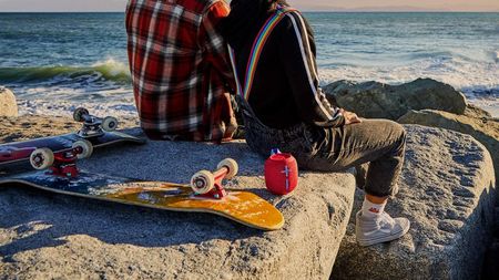 Ultimate Ears Wonderboom 2 review: people sat on a rock by the beach with a speaker and skateboard