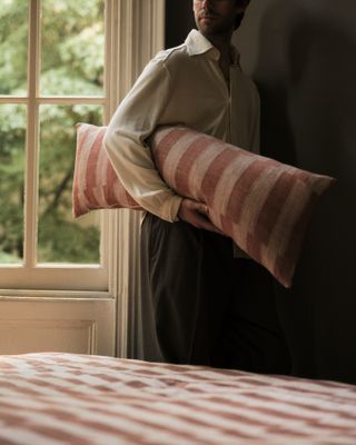 interior stylist colin king holding a striped lumbar pillow from his cultiver collection