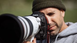 Canon EOS R1 camera held up to a person's face