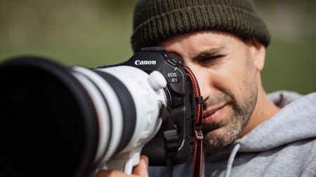 Canon EOS R1 camera held up to a person's face