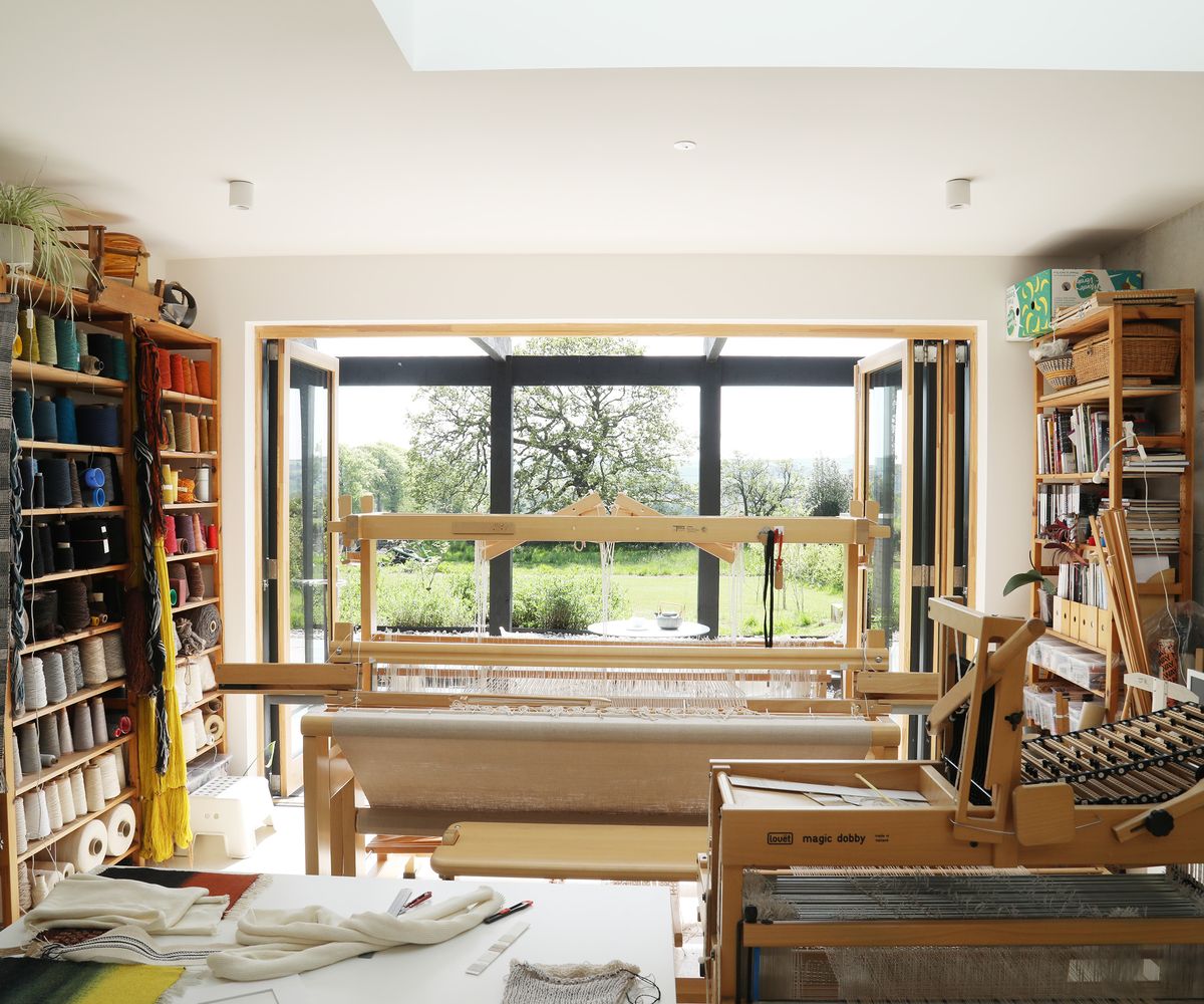 The view out from a home weaving studio with bifold doors fully open and looking out to a garden