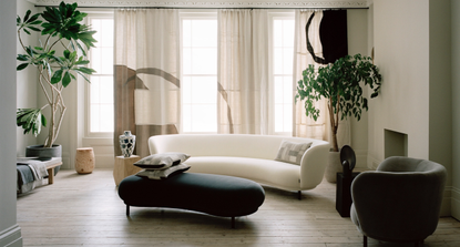 Neutral living room with bespoke geometric curtains, curved white sofa and warm minimalist aesthetic