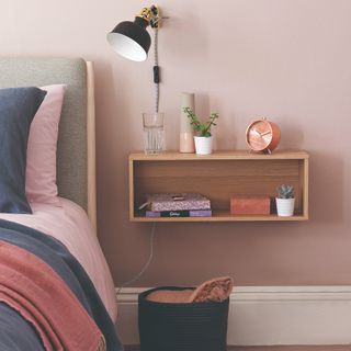 A pink bedroom with a floating cube shelf in place of a bedside table