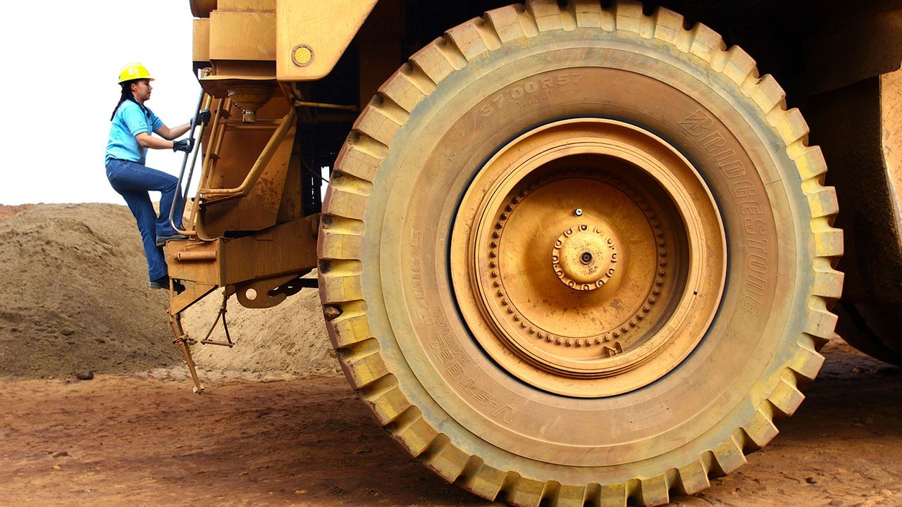 Woman climbing onto an iron ore dump truck © Getty Images