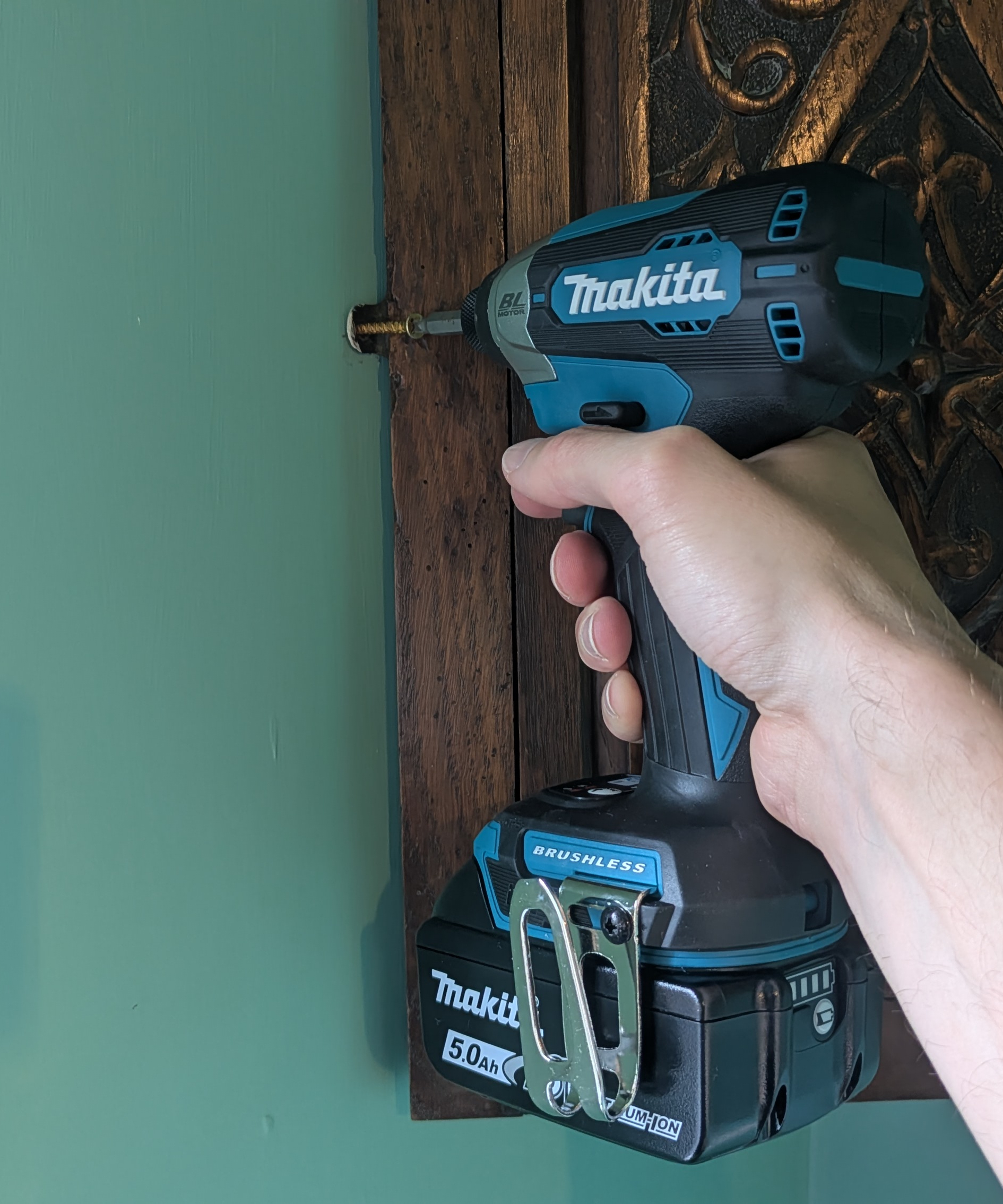 An impact driver being used to install a screw which is holding a cupboard to a wall