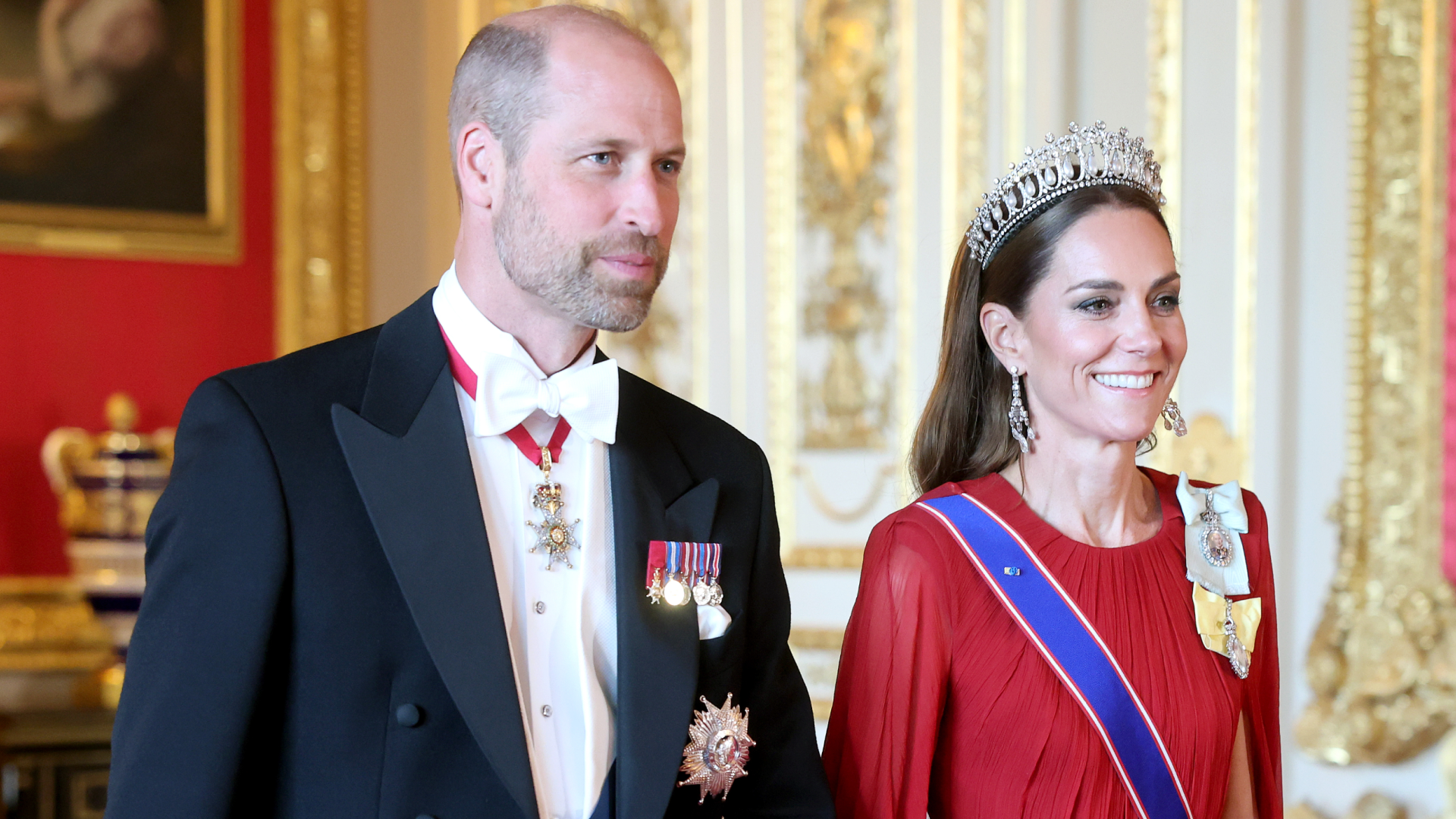 Prince William walking with Princess kate wearing a red gown and tiara at French state banquet