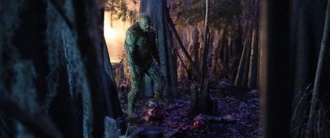 Swamp Thing looms over a decapitated body in a forest.