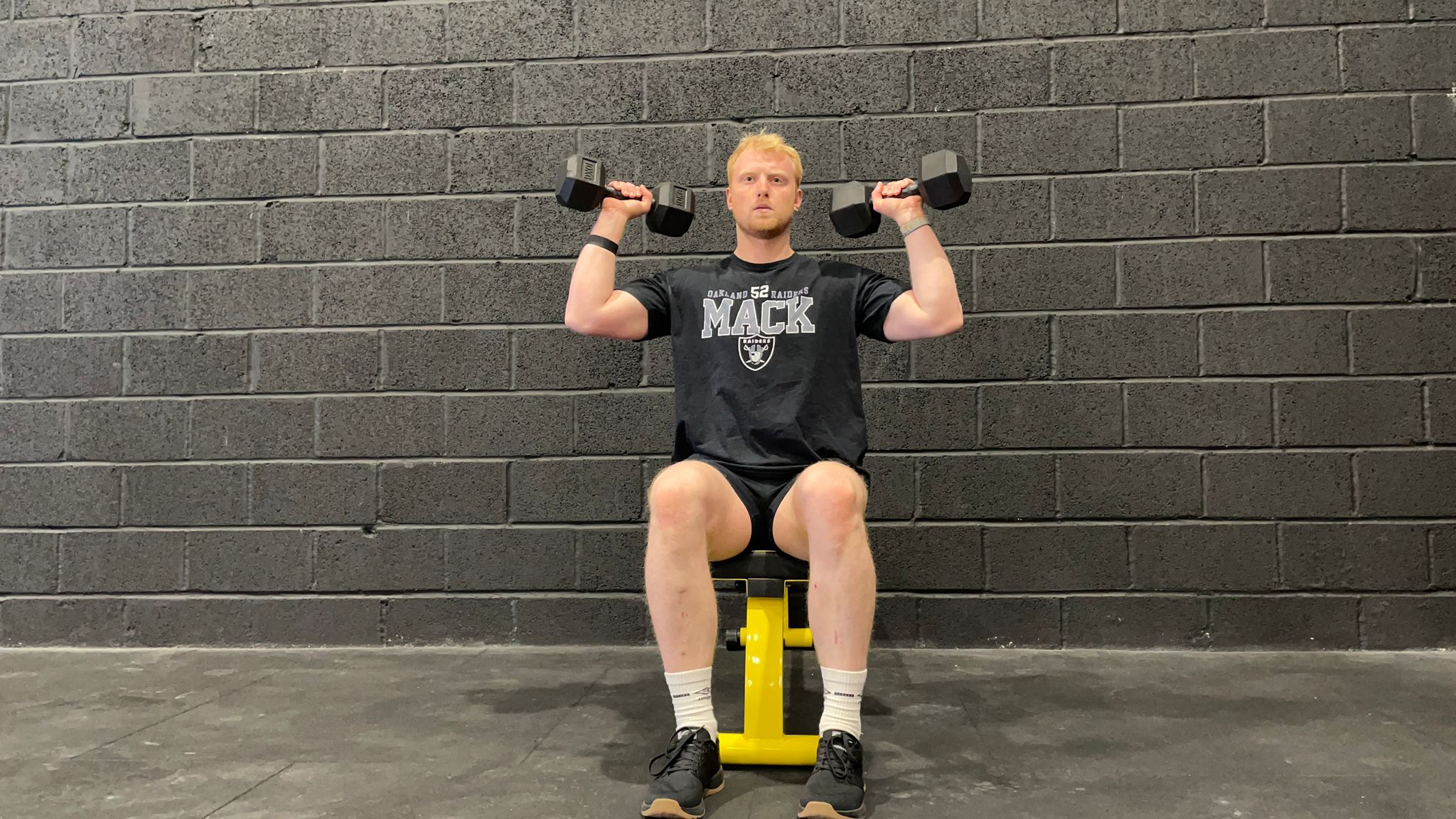 TechRadar fitness writer Harry Bullmore demonstrating a dumbbell shoulder press