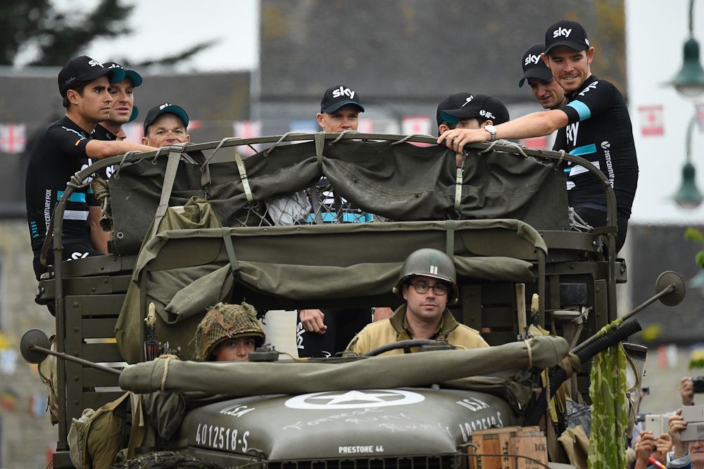 team Sky riders sit in a vintage World War II vehicle on their way to the Tour de France team presentation stage