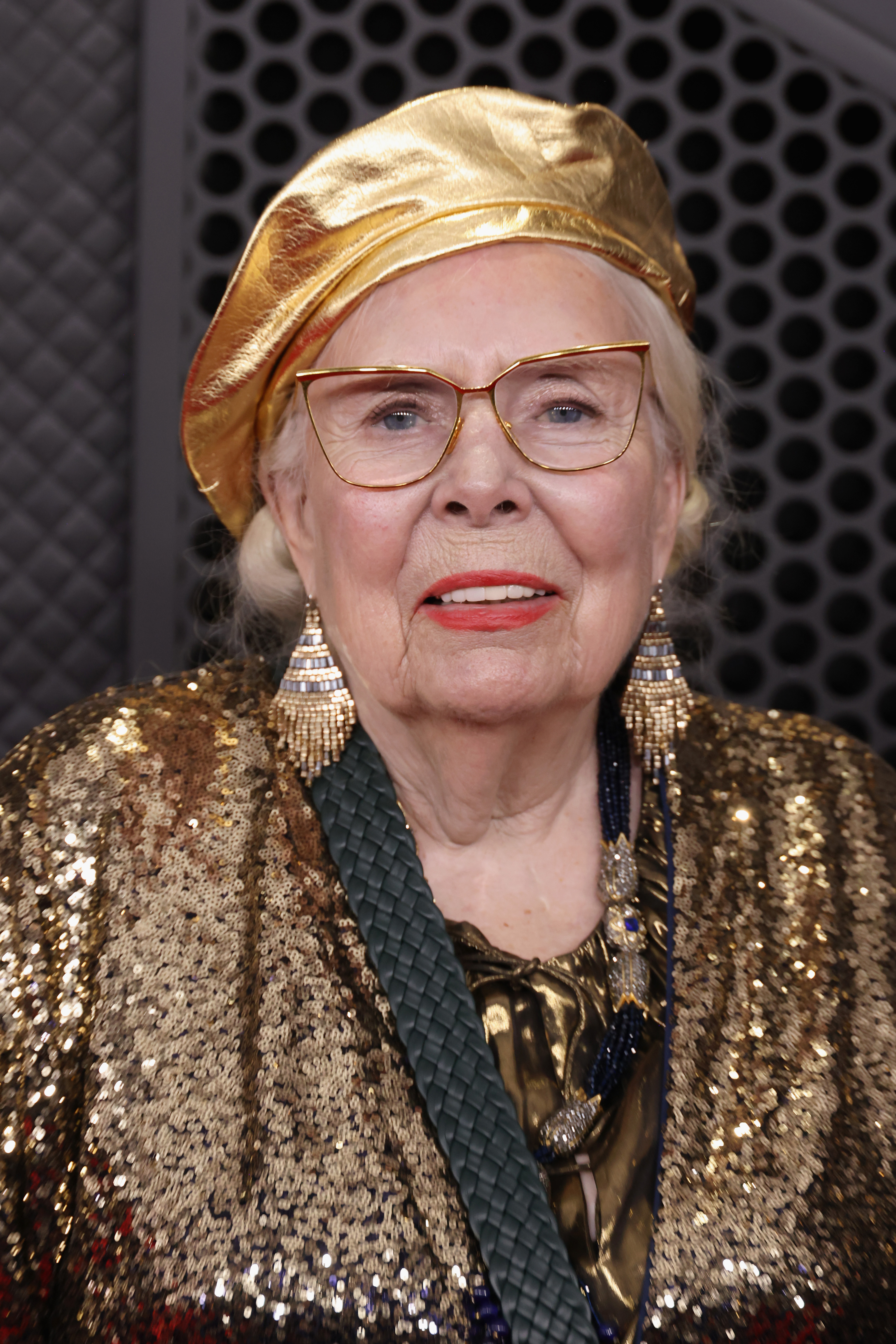 an older white woman with a red lipstick and gold outfit
