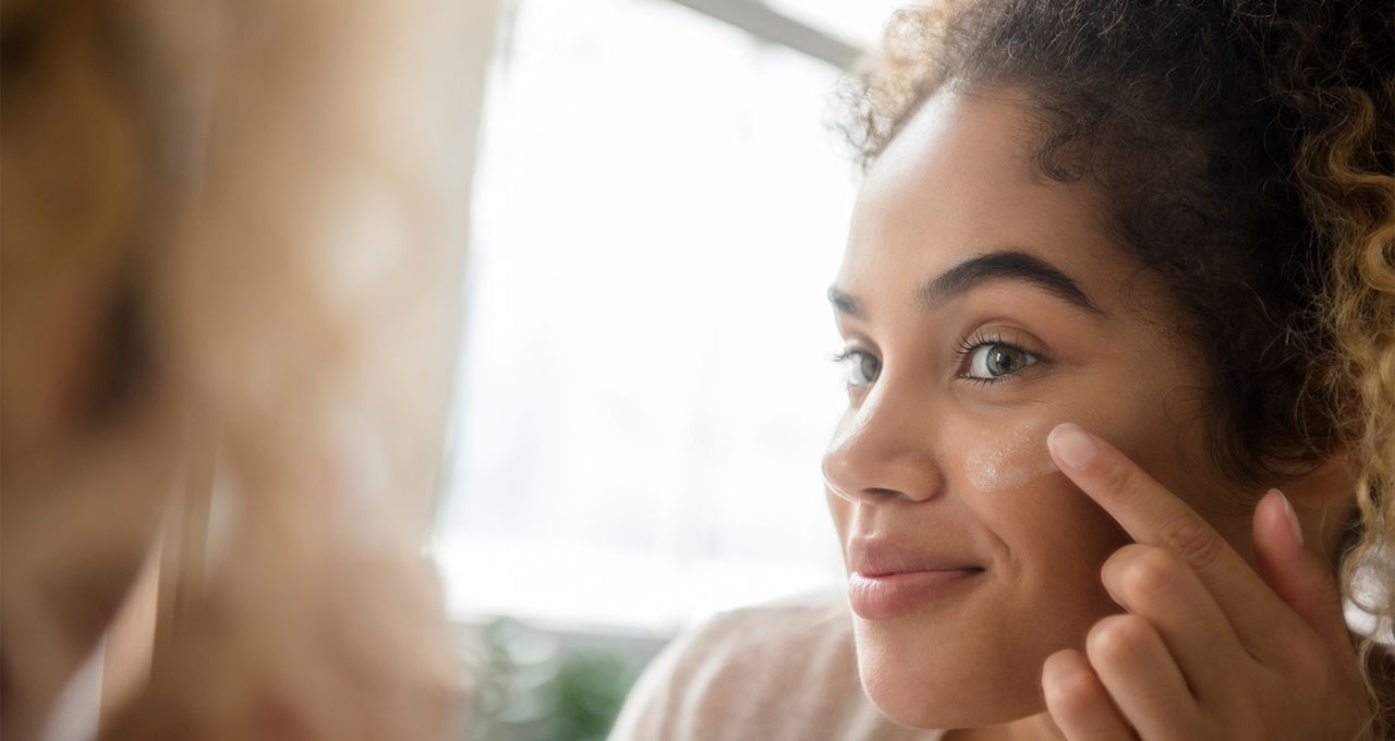 woman applying sunscreen lotion to cheek - stock photo