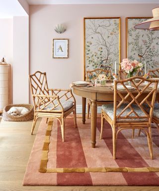 pink painted dining room with a large pink striped rug with bamboo detail and a large dining table with bamboo rattan chairs